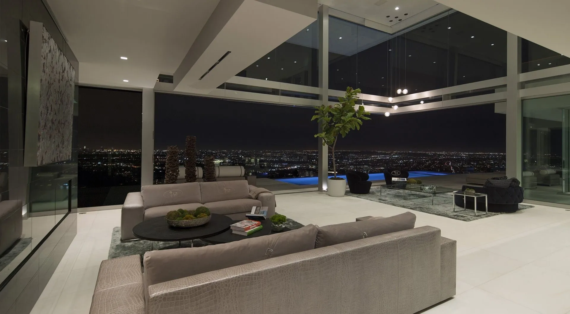Open living room at night with the terrace and pool beyond