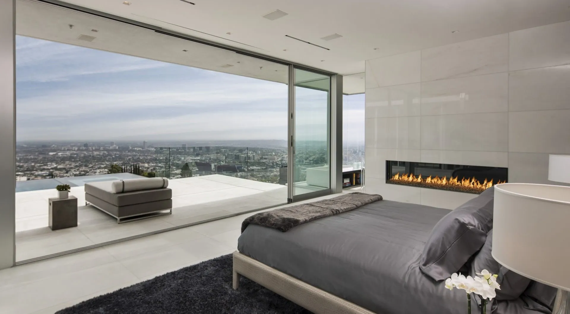 Bedroom with a linear fireplace and city view