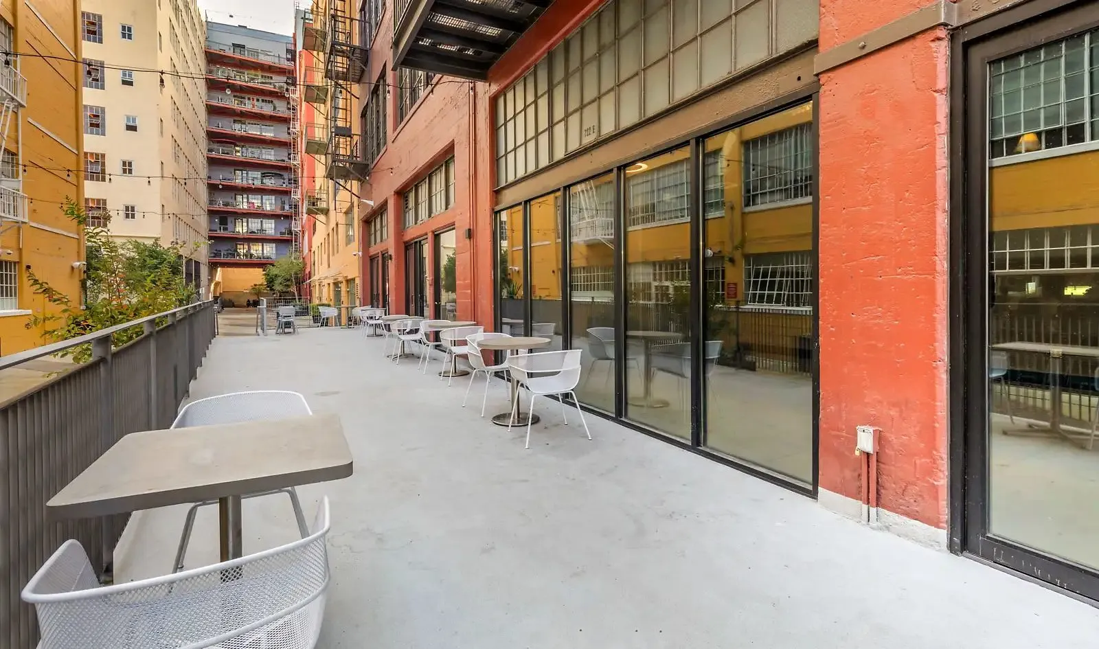 Santee Court courtyard walkway with café tables, string lights, and original steel-framed factory windows