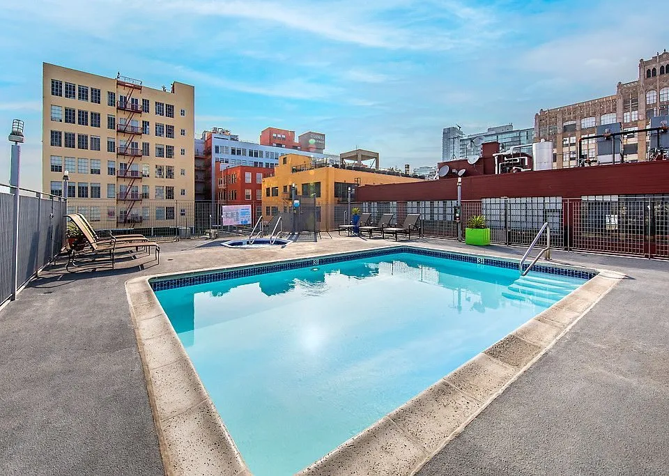 Rooftop pool and spa deck at Santee Court framed by Downtown LA loft buildings